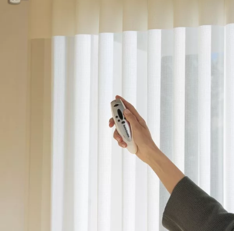 A man holding a remote in hand and move the motorized blinds