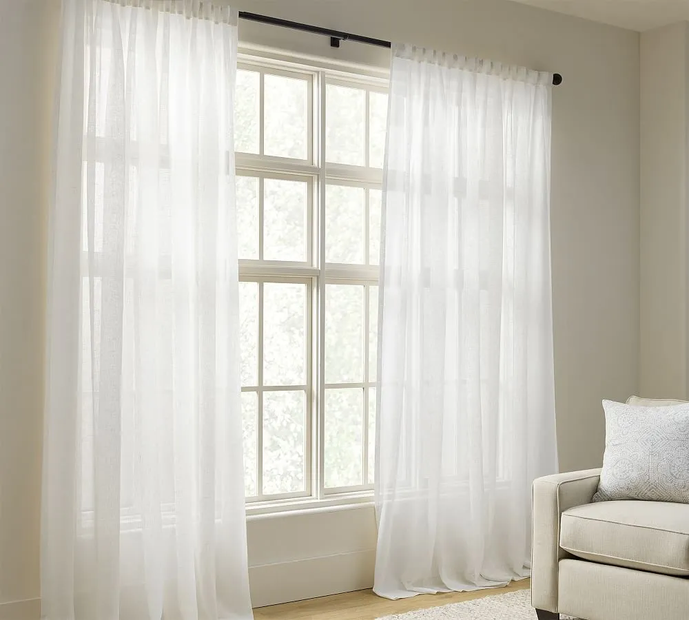 white sheer linen window curtain hanging in front of a white window.